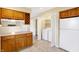 Bright kitchen featuring white appliances, wood cabinets, tiled floor and laundry closet at 7330 Tousley Dr, Indianapolis, IN 46256