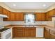 Kitchen area featuring a corner sink, tiled floors, wooden cabinets and view to backyard at 7330 Tousley Dr, Indianapolis, IN 46256