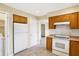 Cozy kitchen featuring white appliances, wood cabinets, and a tiled floor with a laundry closet at 7330 Tousley Dr, Indianapolis, IN 46256
