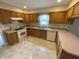 Kitchen featuring wooden cabinets, corner sink, white appliances and tiled floor at 7330 Tousley Dr, Indianapolis, IN 46256