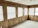 Bright sun room with wood paneled walls and natural light streaming in through multiple windows at 810 W 2Nd St, Anderson, IN 46016