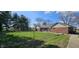 Backyard featuring a well-kept lawn, trees, and a partial view of the home with brick accents at 965 W New Rd, Greenfield, IN 46140