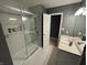 This bathroom features marble tile, a glass shower, a white sink with mirror and a door to another room at 11720 Grenadier Ln, Indianapolis, IN 46229