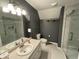 This is a bathroom with a gray wall, white toilet and sink, and a marble tile shower with a glass door at 11720 Grenadier Ln, Indianapolis, IN 46229