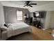 Bedroom features ceiling fan, light grey walls, wood flooring, and is furnished with a bed and entertainment center at 11720 Grenadier Ln, Indianapolis, IN 46229
