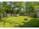 Expansive backyard featuring a lush lawn, wooden fence, mature trees, and inviting fire pit at 3125 N Tacoma Ave, Indianapolis, IN 46218