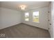 Carpeted bedroom with a ceiling light and two windows that look out over the undeveloped property at 6596 Dogwood Dr, McCordsville, IN 46055