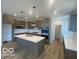 Modern kitchen features an island with pendant lighting, quartz countertops, and stainless steel appliances at 6596 Dogwood Dr, McCordsville, IN 46055