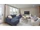 Cozy living room features a plush blue sectional, large windows, neutral tones, and stylish decor at 7348 W County Road 600 Rd # 12-604, McCordsville, IN 46055