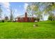 A spacious backyard of the red brick home, featuring a well, patio and lush green grass at 56 Hadley Woodland St, Mooresville, IN 46158