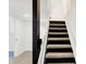 View of the staircase with carpeted steps leading to the upper level, accented by modern black wood at 4360 Guilford Ave, Indianapolis, IN 46205