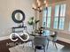 Bright dining room features a round glass table, modern chandelier and shuttered windows at 520 Bridgemont Ln, Carmel, IN 46032