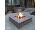 Brick fire pit with granite top and burning fire, located on a patio next to an outdoor kitchen at 520 Bridgemont Ln, Carmel, IN 46032