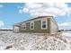 Side and rear view of the green home with a covered patio and snowy yard at 7840 Magnolia St, New Palestine, IN 46163