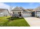Attractive home features stone accents, gray siding, two-car garage, and a lush green lawn in a modern design at 16892 Cattle Hollow Ln, Noblesville, IN 46060