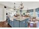 Bright open kitchen featuring white cabinets, a blue island with seating, and modern lighting fixtures at 3441 S Overlook Pass, New Palestine, IN 46163