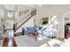 Elegant living room with hardwood floors, a blue sectional sofa, and a grand staircase leading to the upper level at 3441 S Overlook Pass, New Palestine, IN 46163