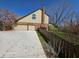 Side view of a home featuring a driveway leading to a garage, with a blooming tree and a wooden fence at 8429 Admirals Cv, Indianapolis, IN 46236