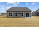 Exterior rear view of a grey home featuring a sliding glass door, small patio, and spacious backyard at 5006 Carmine St, Brownsburg, IN 46112