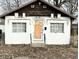 Small home exterior with white painted brick, covered front door, and brown trim at 1214 N Penn St, Muncie, IN 47303