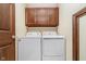 A dedicated laundry area featuring full-sized washer and dryer with wooden cabinets for added storage at 3592 W Smokey Row Rd, Bargersville, IN 46106