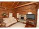 Inviting log cabin living room with a stone fireplace, comfortable sofa, and rustic décor at 7987 N Lasalle Rd, Morgantown, IN 46160
