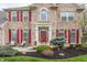 Close-up of a brick home entrance with red shutters, potted plants, and a welcoming front porch area at 10866 Flower Mound Pl, Fishers, IN 46037