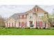 Inviting two-story brick home with red shutters, complemented by a lush lawn and garden landscaping at 10866 Flower Mound Pl, Fishers, IN 46037