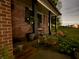 Inviting front porch featuring brick exterior, a rocking chair, and lush landscaping at twilight at 454 Tulip Dr, Mooresville, IN 46158