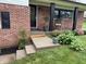 Attractive front porch with brickwork, black door, 'welcome' mat, and well-maintained landscaping at 454 Tulip Dr, Mooresville, IN 46158