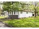 Exterior view of a single-story home with a covered porch and green lawn surrounded by trees at 715 N Warman Ave, Indianapolis, IN 46222