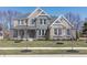 Stunning two-story home featuring a stone facade, blue shutters, covered porch, and professionally landscaped front yard at 78 Chatham Brook Dr, Westfield, IN 46074