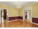 Dining room featuring hardwood floors, decorative molding, and elegant chandelier lighting at 1398 Penny Ln, Greenfield, IN 46140