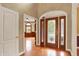 Spacious foyer with gleaming hardwood floors features views of a study with wood paneling and large windows at 1398 Penny Ln, Greenfield, IN 46140