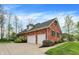 Side view of the home features a two-car garage and lush landscaping, offering privacy at 1398 Penny Ln, Greenfield, IN 46140