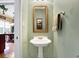 Quaint half bathroom with pedestal sink and decorative mirror at 1398 Penny Ln, Greenfield, IN 46140