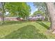 A sprawling backyard with lush green grass, mature trees, and a view of the home's exterior and detached garage at 409 Lansdowne Rd, Indianapolis, IN 46234