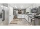 Well-lit kitchen featuring stainless steel appliances, white cabinetry, and wood-look flooring, seamlessly connecting to a cozy living area at 409 Lansdowne Rd, Indianapolis, IN 46234
