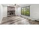 Spacious living room featuring a brick fireplace, large window overlooking lush greenery, and modern wood-look flooring at 409 Lansdowne Rd, Indianapolis, IN 46234