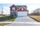 Two-story red brick and siding home with attached garage and landscaping at 4612 Amber Wood Dr, Indianapolis, IN 46235