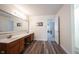 Bathroom featuring dual sinks, wood-look flooring, bright lighting, and doorway to bedroom at 10406 Corning Way, Fishers, IN 46038