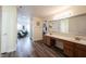 Bathroom featuring dual sinks, wood-look flooring, bright lighting, and doorway to bedroom at 10406 Corning Way, Fishers, IN 46038