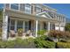 Inviting front porch with decorative columns, seating, and lush landscaping surrounding this charming home at 10406 Corning Way, Fishers, IN 46038