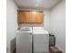Functional laundry room with upper cabinets, modern washer and dryer, and wood-look floors at 10406 Corning Way, Fishers, IN 46038