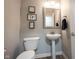 Elegant powder room featuring a pedestal sink, modern toilet, and stylish wall decor at 10406 Corning Way, Fishers, IN 46038