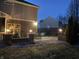 Evening view of a backyard patio with seating area, firepit, and landscape lighting at 11617 Andreas Ct, Fishers, IN 46038