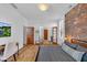 Spacious bedroom with multiple doors, wood floors, exposed brick, and a modern desk at 304 N College Ave # Apt A, Indianapolis, IN 46202