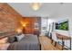 Inviting bedroom features an exposed brick wall, modern furniture, wood floors, and a stylish light fixture at 304 N College Ave # Apt A, Indianapolis, IN 46202