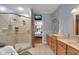 Well-lit bathroom with a glass enclosed shower, double vanity, and a view into the connected bedroom at 304 N College Ave # Apt B, Indianapolis, IN 46202