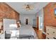 Large bedroom with exposed brick walls, ceiling fan, hardwood floors and doorways leading to other rooms at 304 N College Ave # Apt B, Indianapolis, IN 46202